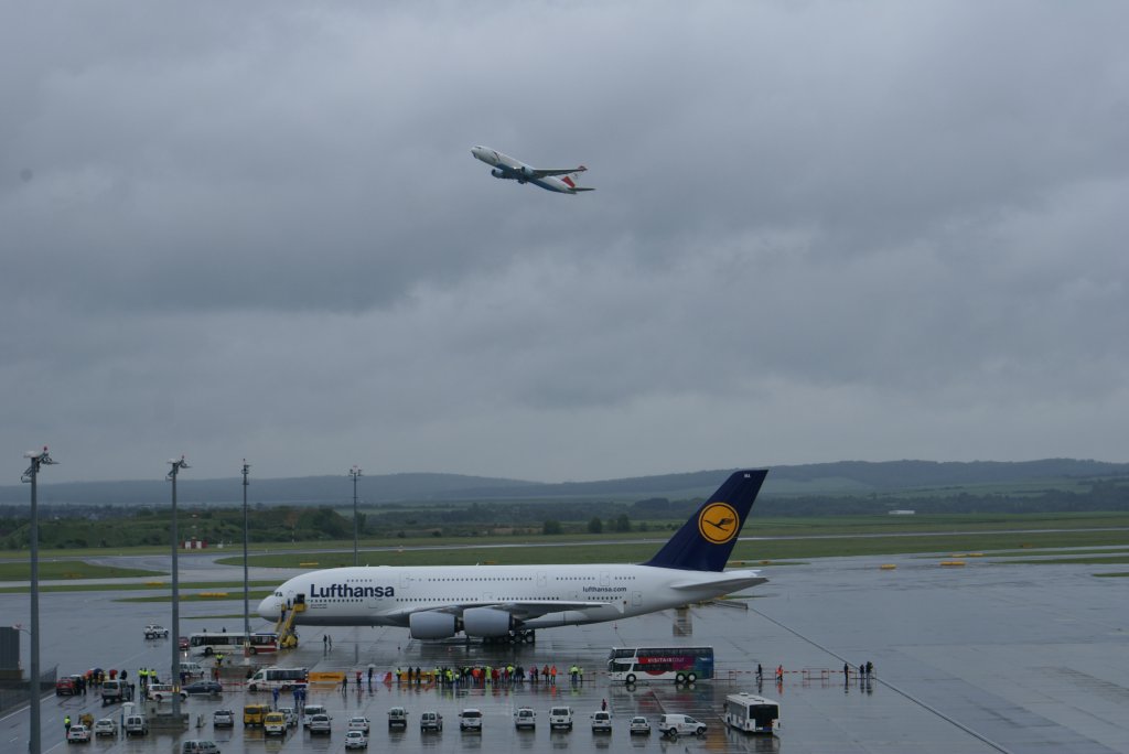 Airbus A380-800 D-AIMA der Lufthansa steht auf seiner Parkposition als ber ihm eine Boeing 767 der Austrian Airlines gerade gestartet ist. 2.6.2010