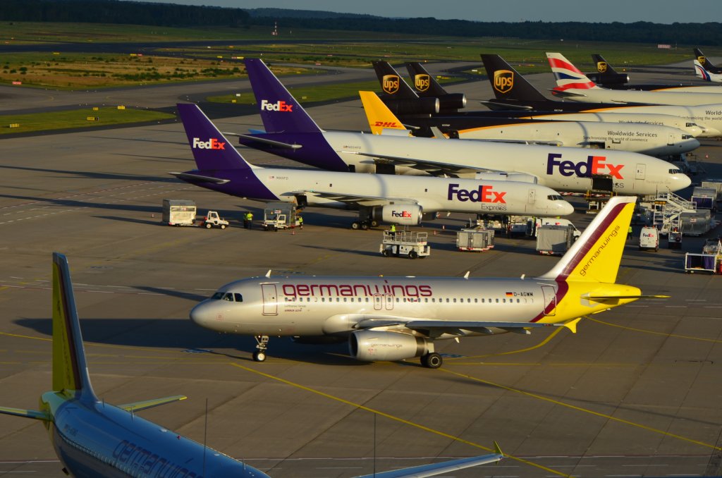 Der Airbus A 319 von Germanwings hat seine Parkposition am Terminal 1 verlassen, um zum Start zu rollen. Im Hintergrund diverse Frachtflugzeuge, die fr den Nachtflug beladen werden. (Aufnahme 27.08.2012).