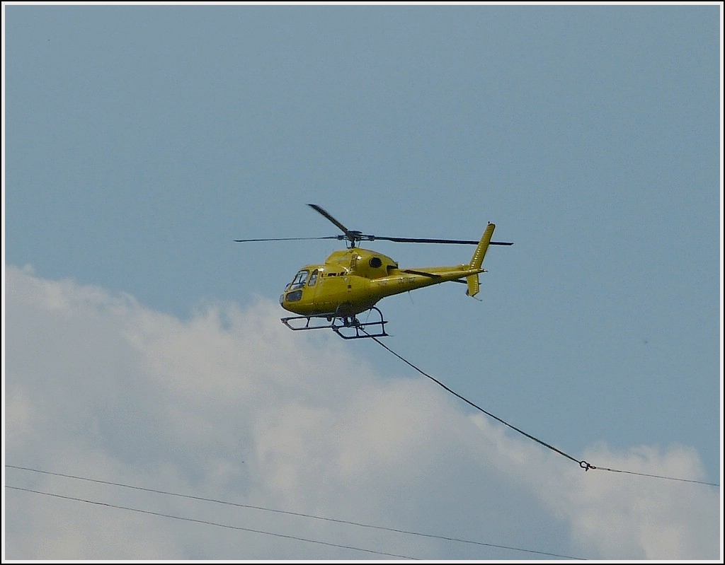 Ein mir unbekannter Hubschrauber mit Hochspannungskabel im Schlepp, zieht diese von einem Masten zum anderen ber eine Hgeligelandschaft im Norden von Luxemburg.  27.05.2013