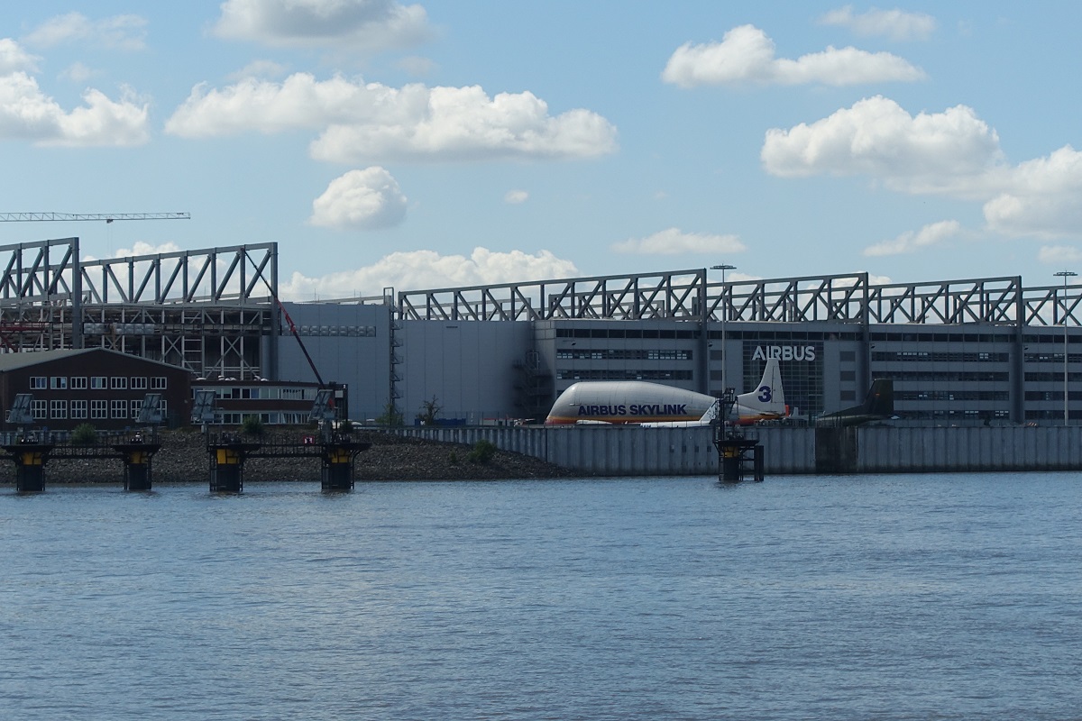 Hamburg am 9.8.2022: mit dem Schiff elbabwärts, hinter der Flutschutzmauer Blick auf einen Teil des  Airbusgeländes auf Finkenwerder /