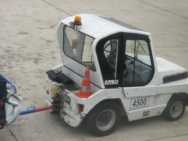 Das ist ein Bild vob einem Gepckwagenzieher beim einladen neber dem Flugzeug am Flughafen in Sevillia