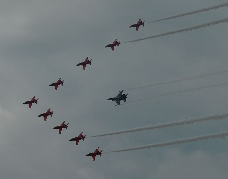 Leider vor dunklen, tiefhngenden Wolken fliegt diese seltene Formation aus Red Arrows und einer F-16 vor. Die F-16 wird von  Mickey  Artiges, dem belgischen F-16 Demo-Piloten geflogen. Das Bild stammt vom 20.07.2008