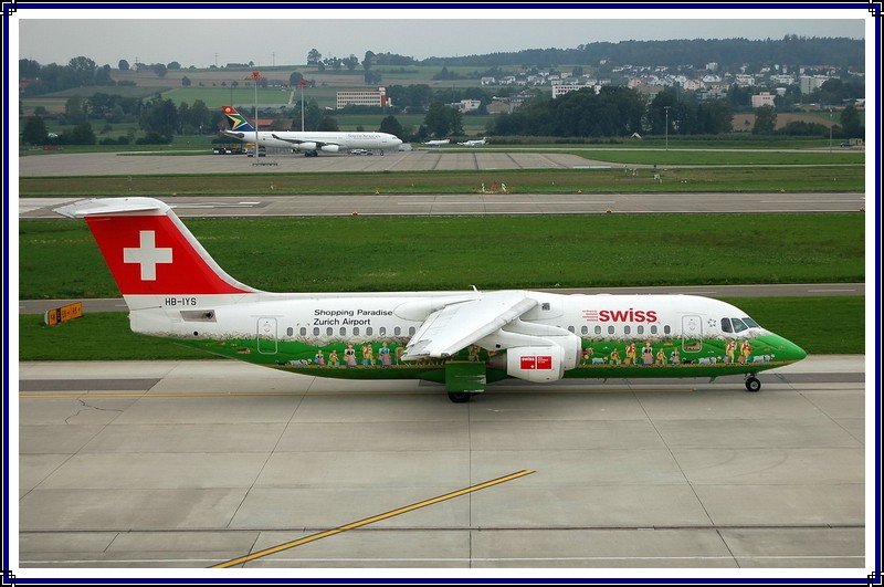 Swiss International Air Lines, HB-IYS, BAE Systems Avro 146-RJ 100. Werbung fr das Shopping Paradies am Flughafen Zrich. Eine sehr schne und auffllige Bemalung des  Jumbolinos . Im Hintergrund steht ein Airbus A340 von South African Airways. 6.9.2006.