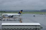 Lufthansa Airbus A380-800 D-AIMA der Lufthansa steht auf seiner Parkposition w�hrend im Hintergrund bei ihm eine Fokker F100 vorbei rollt. 2.6.2010