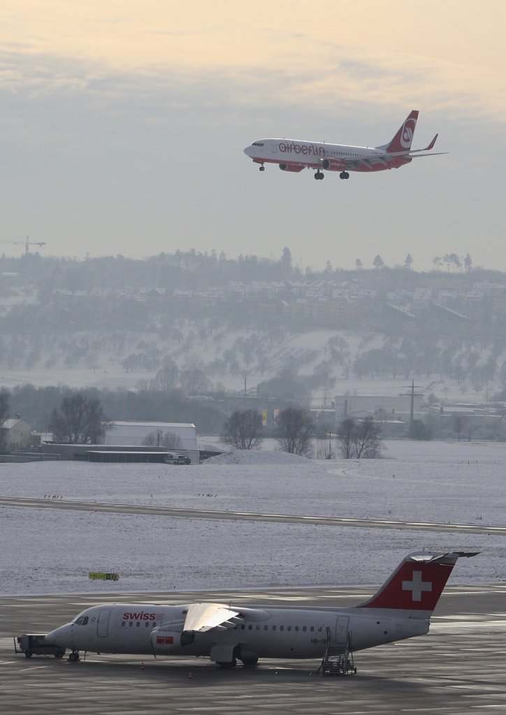 Die Air Berlin Boeing 737-808 D-ABBX landet in Stuttgart am 28.11.10, auf dem Vorfeld steht der Swiss Avro Regional Jet RJ100 mit der Kennung HB-IXR. 



