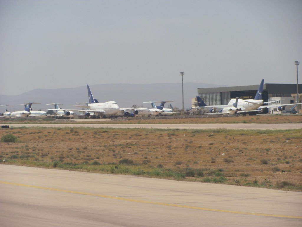 Kurz vor dem Start der Germania Boeing 737-75B von Damaskus nach Aleppo sieht man auf einem Teil des Flughafens den Groteil der SyrianAir Maschinen. Auf Grund des US-Embargos auf Ersatzteilen der Flugzeuge mssen 6x Boeing 727-200/adv, 2x Boeing 747SP und 2x Airbis A320-200 stillgelegt werden. 
Auch zwei Maschinen des Types Tupolev Tu-154M, die wegen Unwirtschaftlichkeit stillgelegt sind, stehen versteckt hinter dem Airbus A320. (Damaskus 15.04.2010)