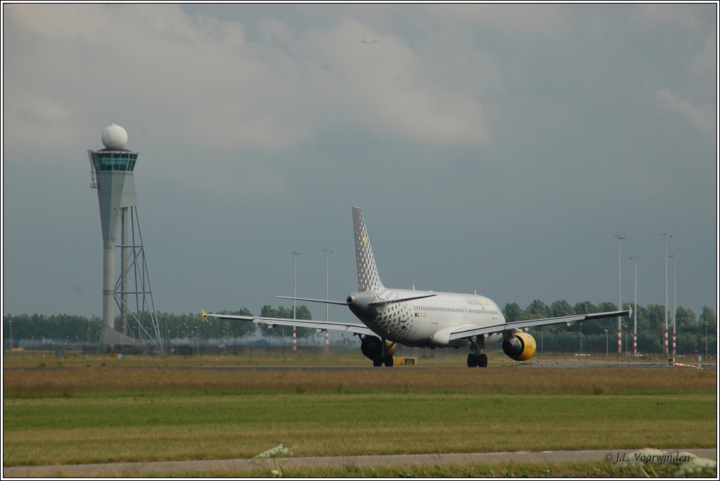 Vueling Airbus A320-211 EC-ICR fhrt nach der Landung auf der  Polderbaan  (18R) zum Empfangsgebude des Flughafens Schiphol Amsterdam; links im Bild der Kontrollturm dieser Piste (13. Juni 2011).