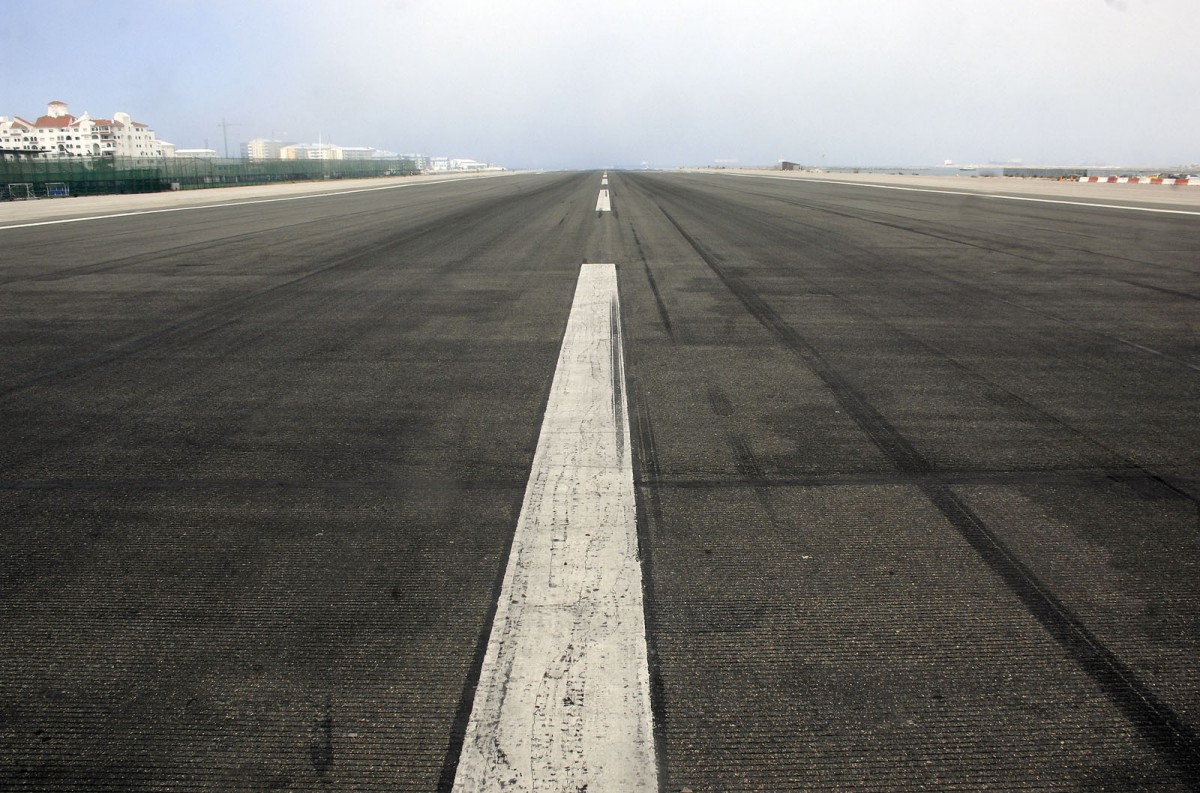 Flughafen Gibraltar. Aufnahme: Juli 2014. Da sich die Hauptverkehrsstraße nach Gibraltar und die Landebahn des Airports kreuzen, steht hier der Verkehr mehrmals am Tag still