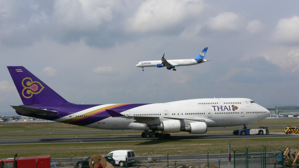 HS-TGR Thai Airways Boeing 747-4D7 - Sirwattana - am 12.04.2012 in Frankfurt auf dem Weg zum Terminal 1. Weiter sieht man eine Boeing 757 von Condor im Landeanflug.