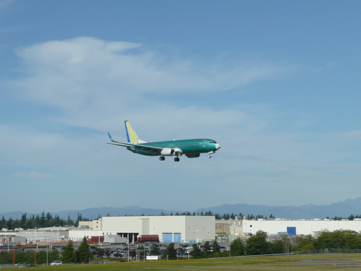 Noch unlackierte B737 im Landeanflug auf das von Boeing als Werksflugplatz benutzte Paine Field, im Hintergrund das Boeing-Flugzeugwerk in Everett. Die B737 wird im Werk Renton montiert. 
3.9.2010