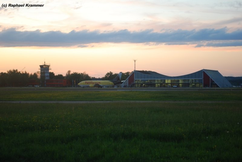 Die TuiFly 737 mit der Leipzig Werbung ist am Abend des 16.05.09 gerade aus Hamburg auf dem Flughafen Memmingen (Allgu Airport, FMM) angekommen. Im Hintergrund links der Tower und rechts das Terminal, welche noch aus Bundeswehrzeiten stammen. Man sieht es dem Terminal nicht mehr an, dass es sich dabei um eine umgebaute Wartungshalle handelt.