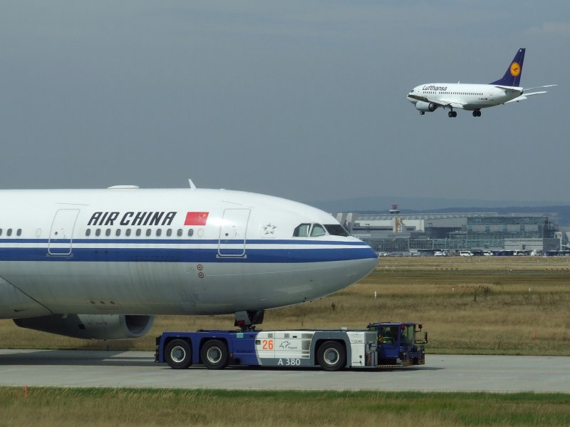 Frankfurt am Main am 07.08.2008. Eine Boeing 737 der Lufthansa landet, whrend ein Airbus A 330 der Air China auf dem Rollfeld unterwegs ist.