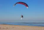 Motorschirmpilot im scheinbaren Wettflug mit einer Möwe am Strand von Ahlbeck. - 12.03.2014